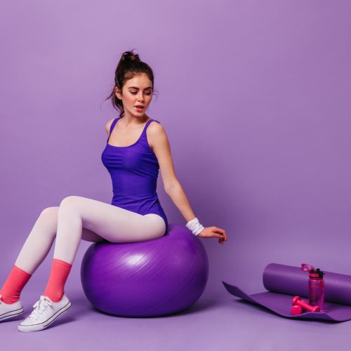 woman-in-white-leggings-and-violet-bodysuit-sits-on-fit-ball_197531-16595